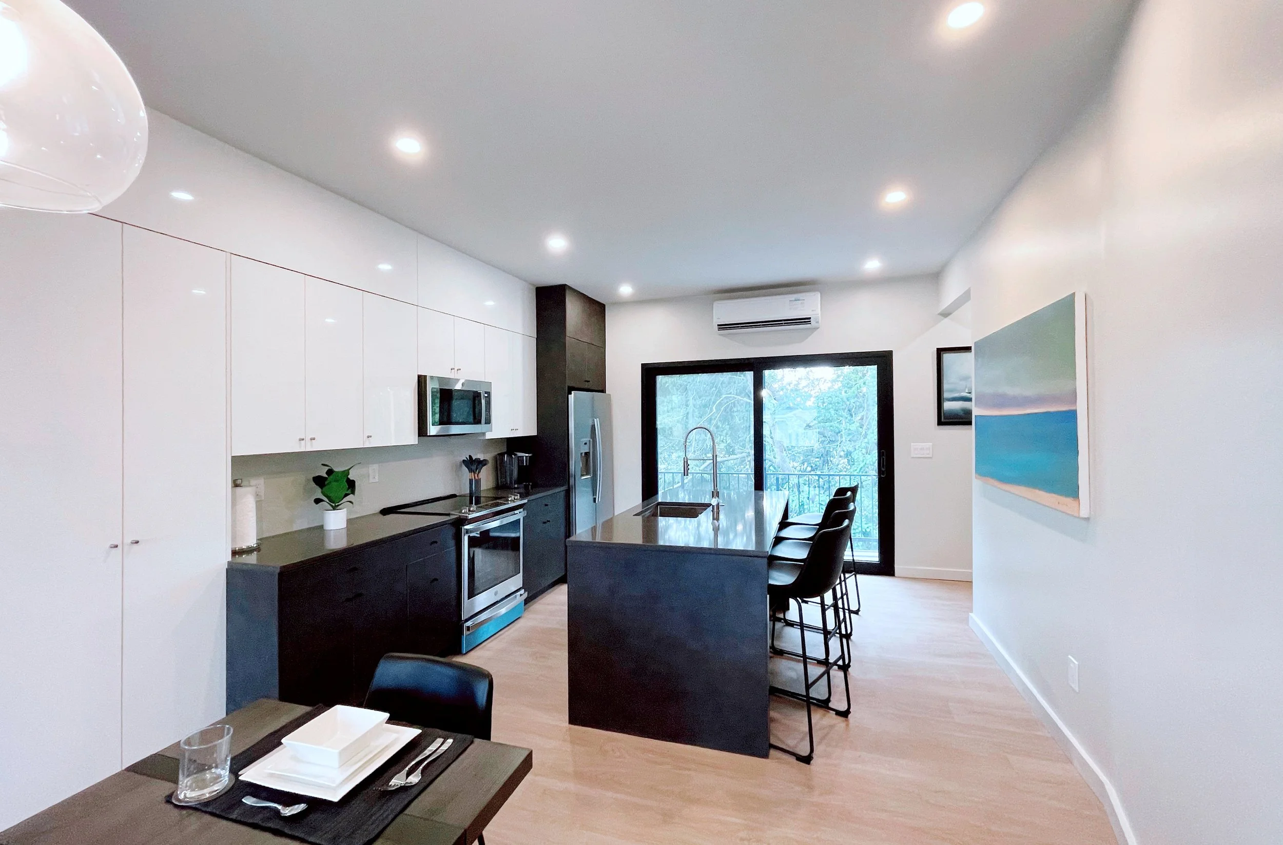 Townhome kitchen with island, dark cabinets, sliding glass door to balcony with treetop views